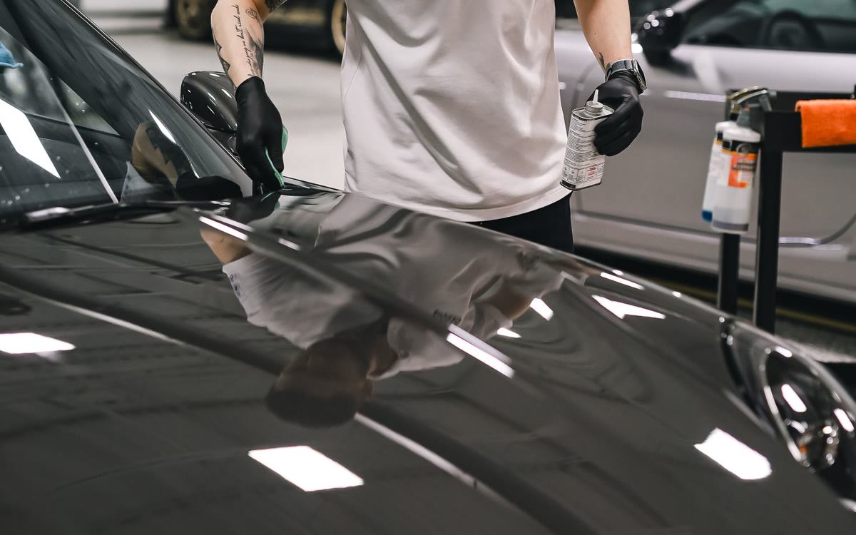 An applicator working on reflective dark paintwork