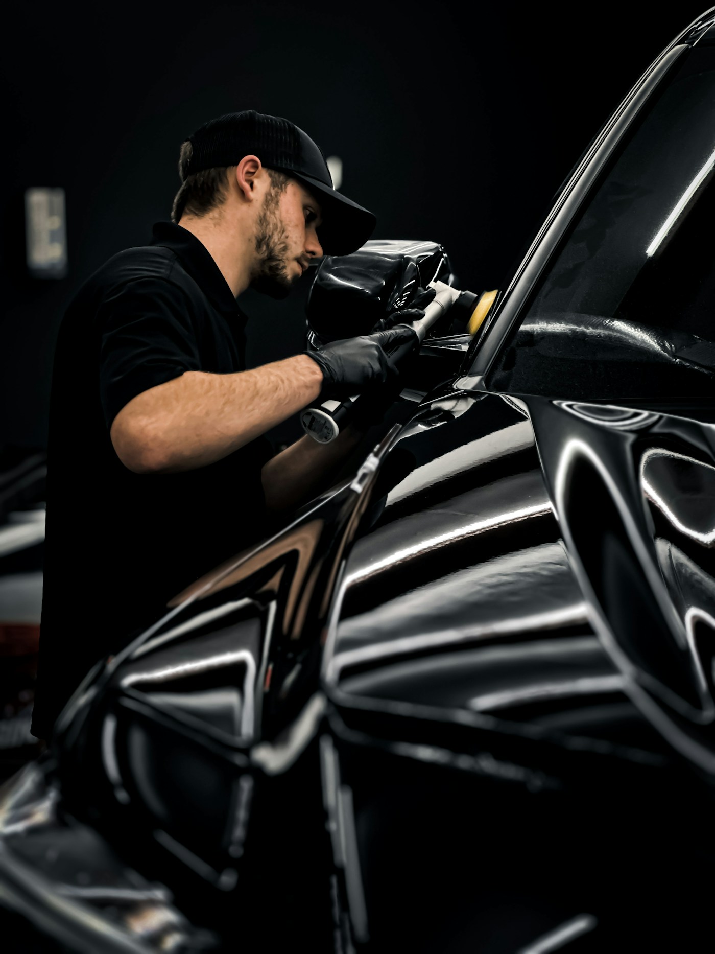 A machine polisher working on reflective black paintwork