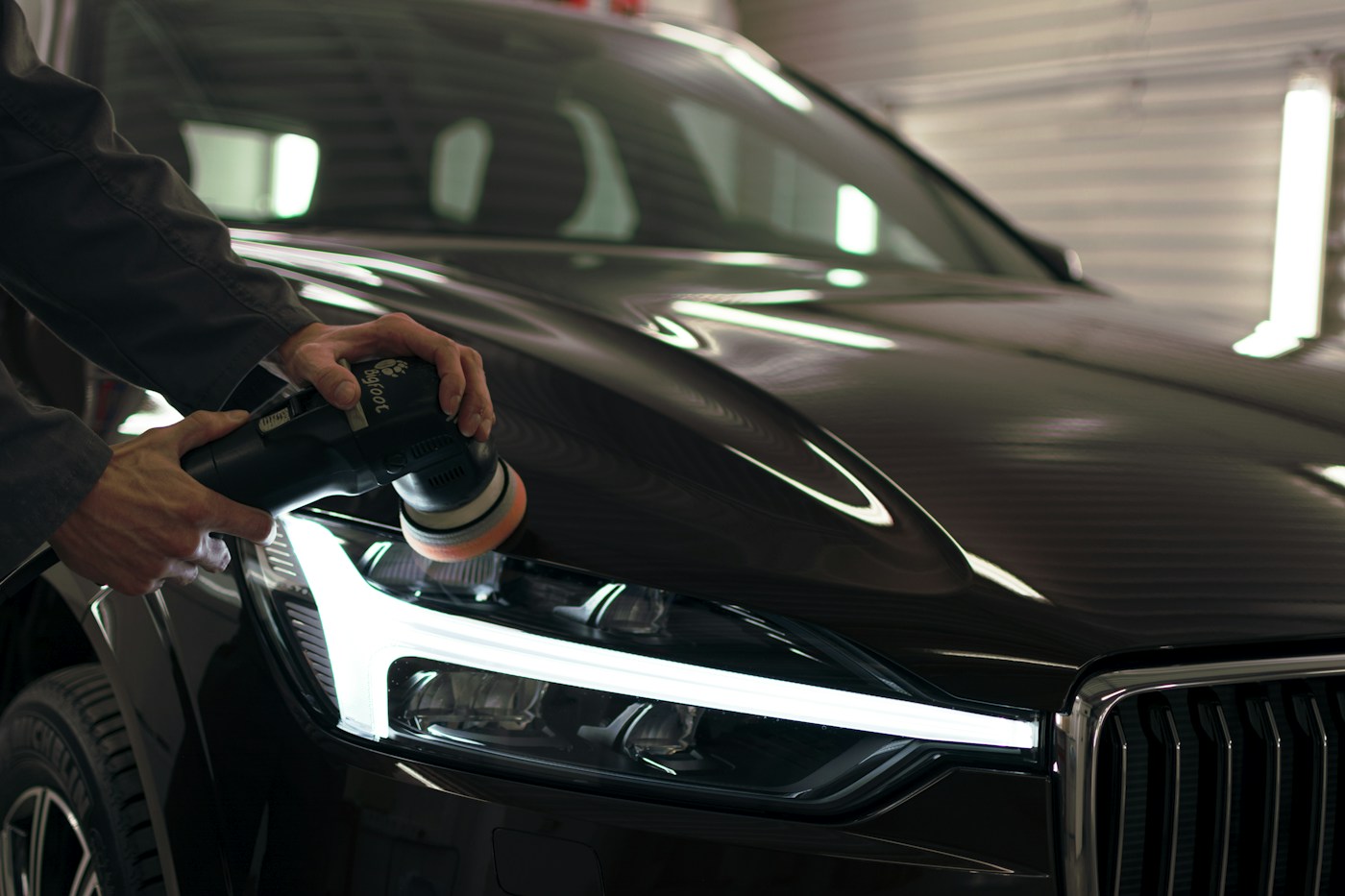 Machine polishing the bonnet of a dark Volvo